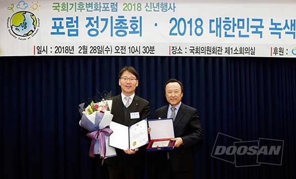 두산중공업 에너지환경담당 박칠규 상무(왼쪽)가 서울 국회의원회관에서 열린 ‘2018 대한민국 녹색기후상 시상식’에 참석해 국회기후변화포럼 홍일표 대표의원으로부터 기업부문 산업통상자원부 장관상 수상 후 기념촬영을 하고 있다. [사진=두산중공업]